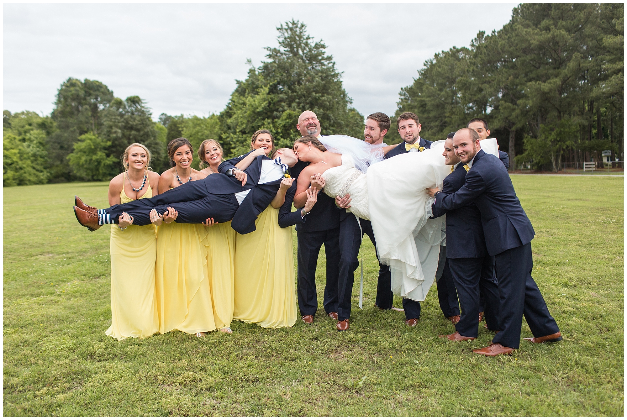 bridal party holding bride and groom