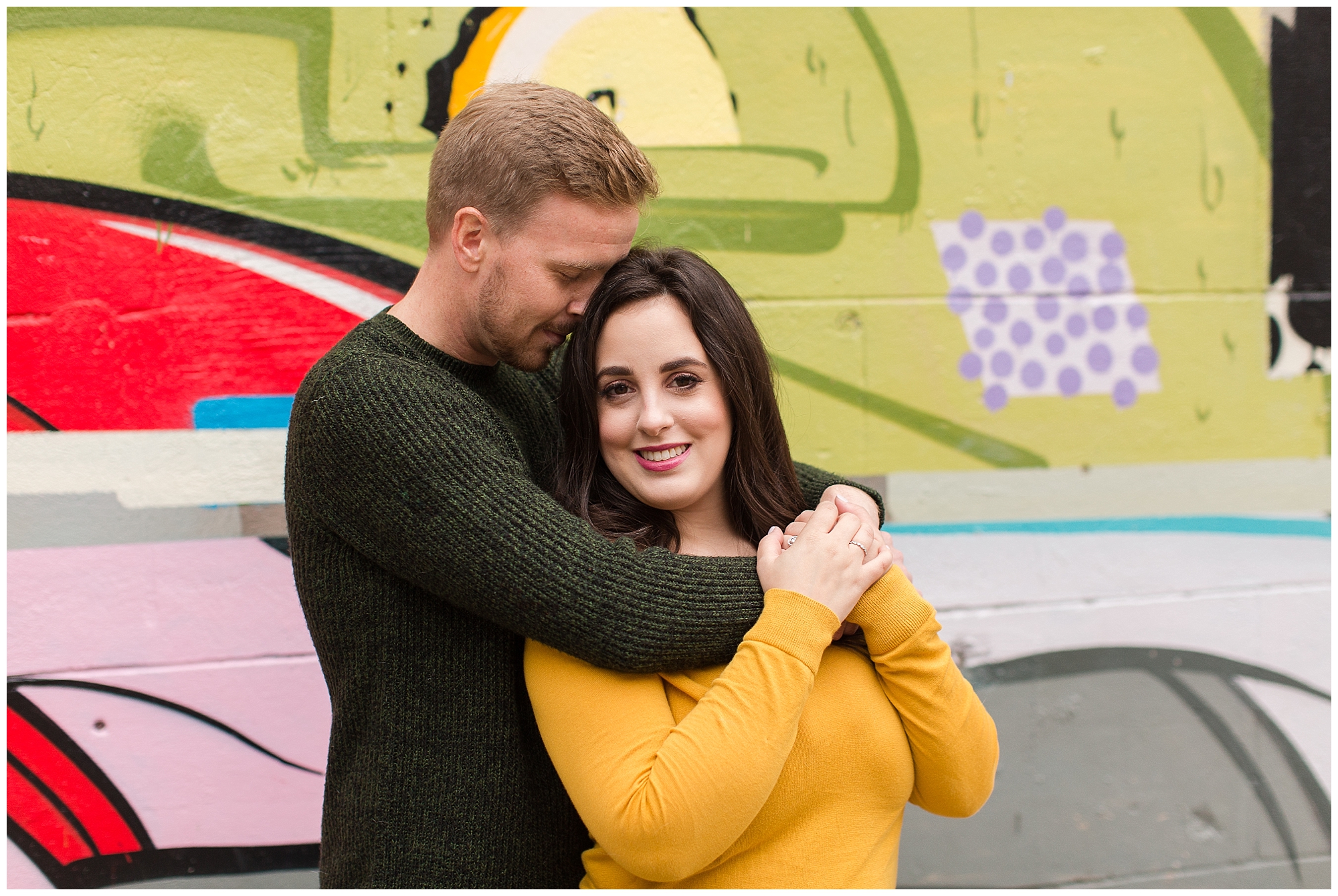 couple posing in front of graffiti wall